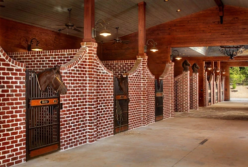 Exposed brick barn aisle with mahogany arched doorway stall fronts