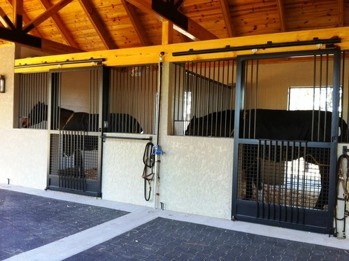 Barn aisle with modern white and gray stall fronts featuring vertical bar doors