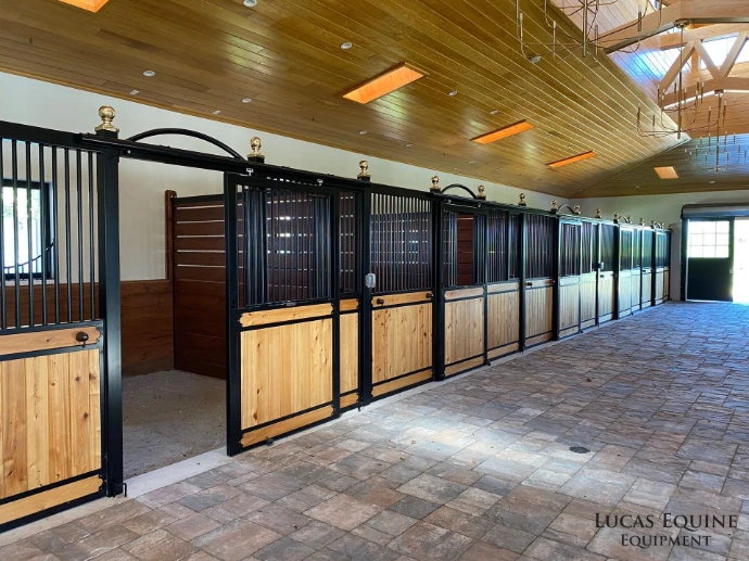Black metal stall fronts with natural pine lower panels in elegant barn with decorative wood ceiling