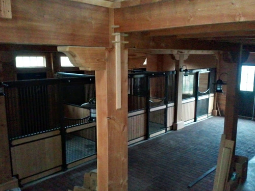Black metal stall fronts with natural pine lower panels in barn with exposed timber beams