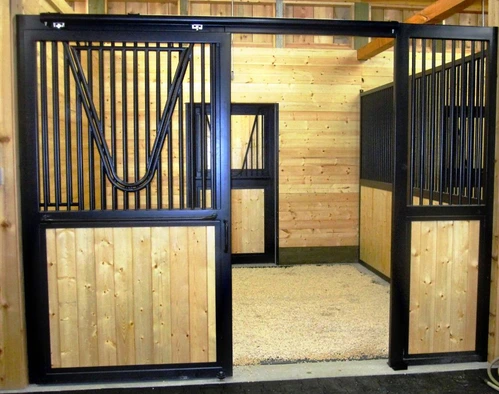 Natural pine stall front with black vertical bars and open sliding door revealing interior