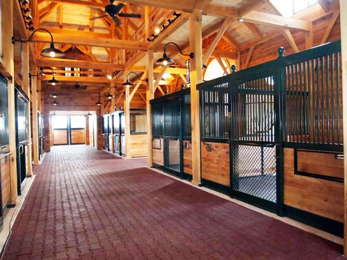 Black metal stall fronts with natural wood lower panels and wire mesh doors in timber-frame barn