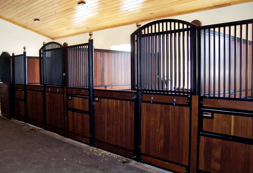 Black metal curved stall fronts with rich mahogany lower panels in elegant barn corridor