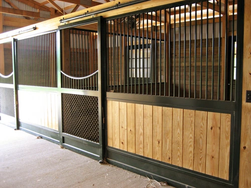 Black metal stall fronts with natural pine lower panels and decorative rope hammocks in white interior barn
