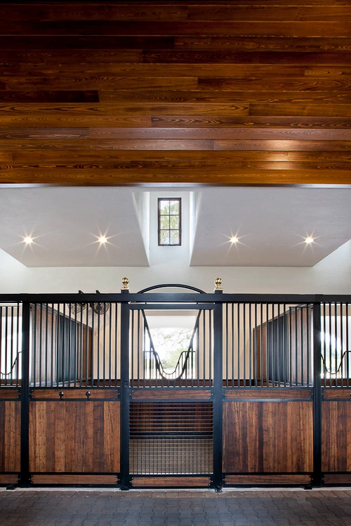 Black metal arched stall front with natural pine lower panel under white vaulted ceiling with skylights