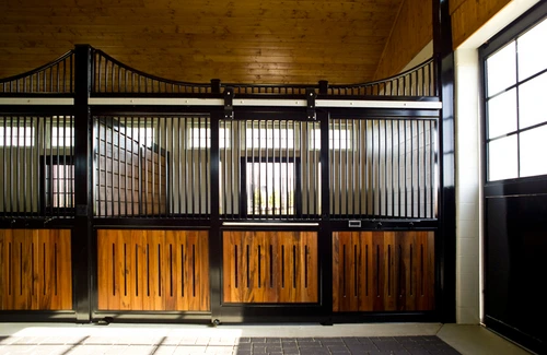 Black metal curved stall fronts with rich mahogany lower panels in luxury barn with rounded ceiling details