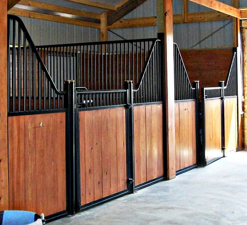 Black metal stall fronts with rich mahogany lower panels and vertical bar upper grills in covered aisle