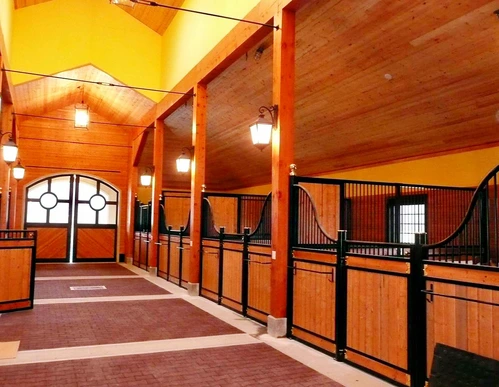 Black metal arched stall fronts with mahogany lower panels in elegant barn with decorative orange ceiling