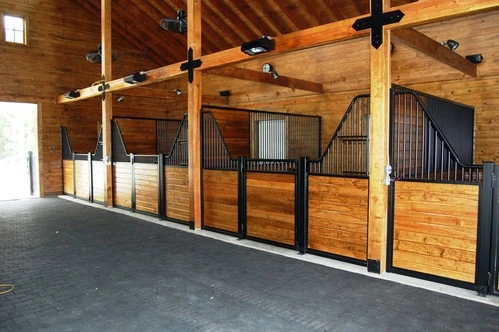 Black metal stall fronts with rich wood lower panels in timber-frame barn with exposed beams