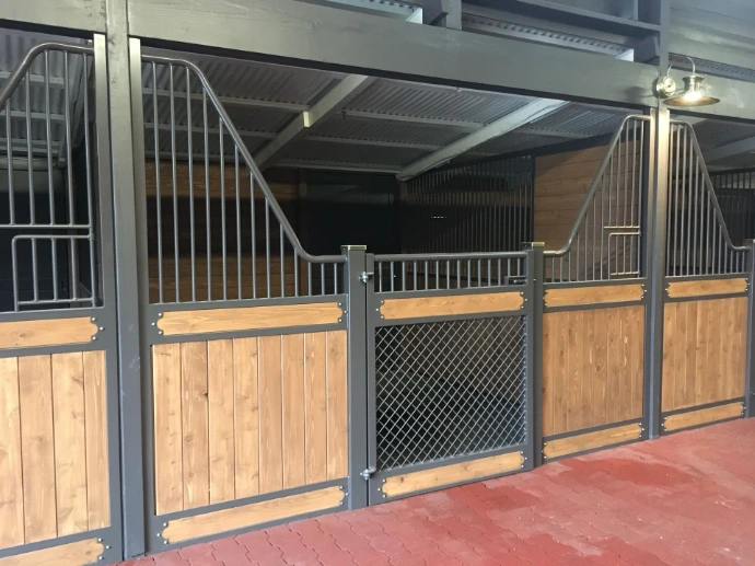 Gray metal stall fronts with natural pine lower panels and wire mesh sliding doors in industrial barn