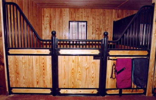 Dark mahogany stall front with black vertical bar upper grill in wood-paneled barn interior