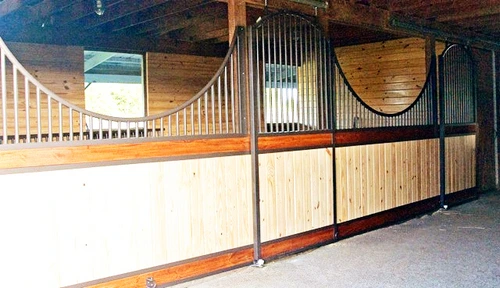 White and natural pine stall fronts with black vertical bar upper grills in bright barn interior