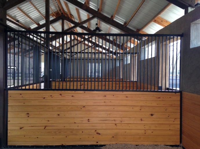 Black metal stall front with vertical bar upper grill and decorative elements in natural pine barn