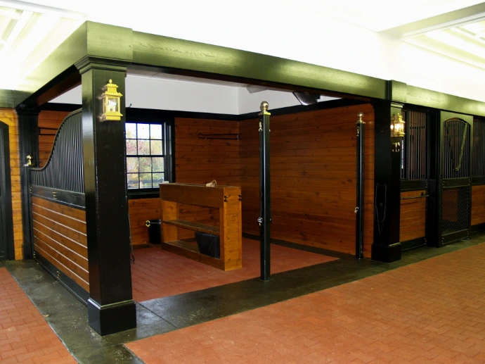 Green powder-coated metal stall fronts with mahogany wood lower sections and black upper grills in modern barn