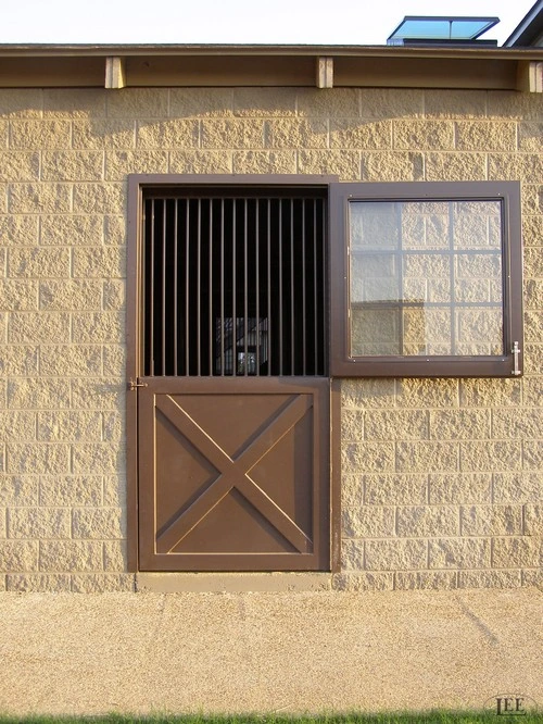 Natural wood sliding door with vertical slats and upper window with black bars on limestone wall