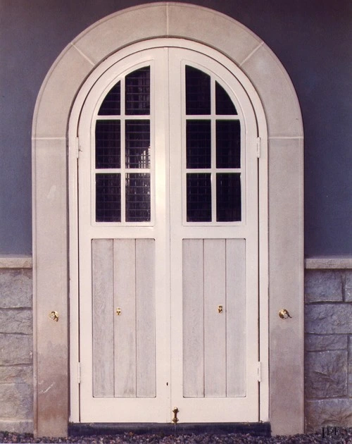 White painted double French doors with divided glass panes flanked by dark shutters