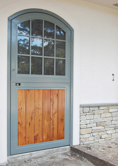 Mint green Dutch door with upper window and natural wood lower panel on stone wall