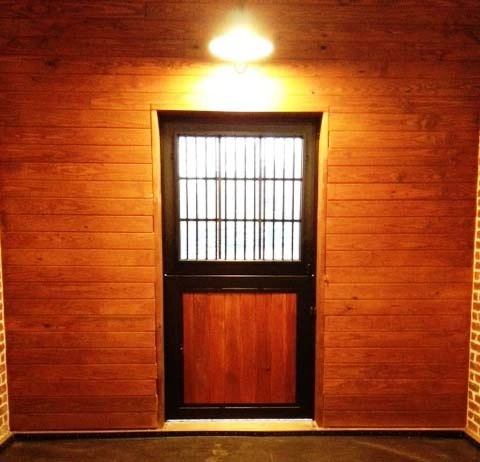 Rich mahogany sliding door with black metal vertical bar upper grill on natural wood wall