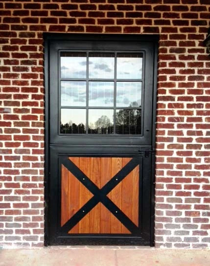 Dark gray metal Dutch door with multi-pane window and natural wood X-pattern lower panel on red brick