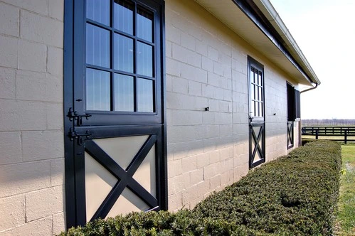 Black metal door with X-brace design on white painted barn exterior