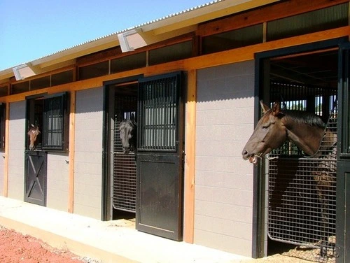 Modern barn exterior with black metal mesh Dutch doors under covered pavilion with giraffe visible