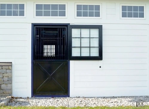 Navy blue Dutch door with X-pattern lower panel centered on white barn with multi-pane window