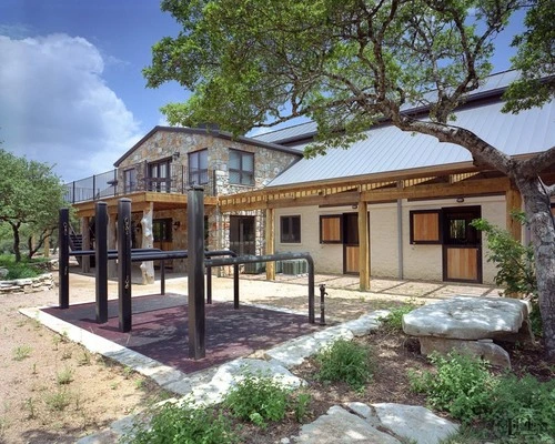 Stone and cream barn with covered walkway featuring natural wood Dutch doors under timber pergola