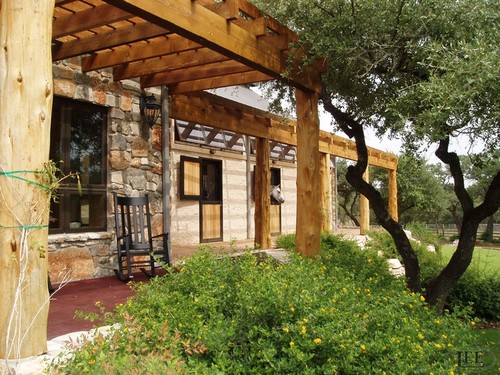 Rustic outdoor barn area with timber-frame pavilion and stone archway openings with black metal grills