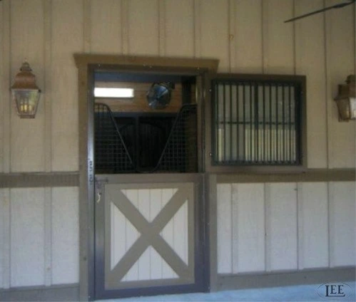 Beige barn exterior with natural wood Dutch door featuring corrugated metal grill and X-pattern lower section