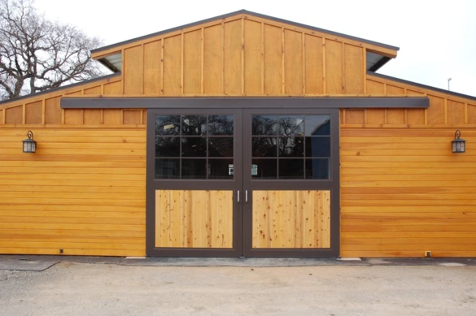 Natural cedar siding barn with dark gray framed doors featuring upper windows and X-pattern