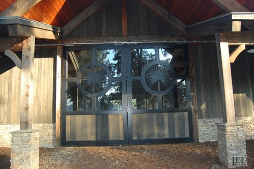 Black framed glass double doors with circular decorative elements under timber-frame pavilion