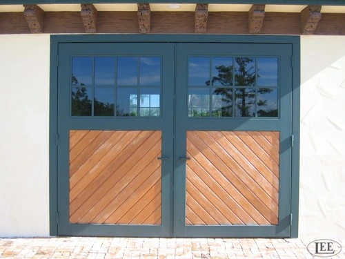 Blue-gray framed double doors with upper glass and lower diagonal wood panels on white stucco