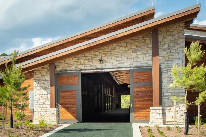 Modern barn with black and natural wood horizontal panel sliding doors on stone building