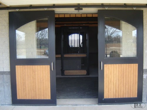 Black metal framed sliding doors with glass panels and beige wood lower sections in arched openings