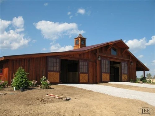 Red-brown wood barn exterior with covered opening and natural wood sliding doors