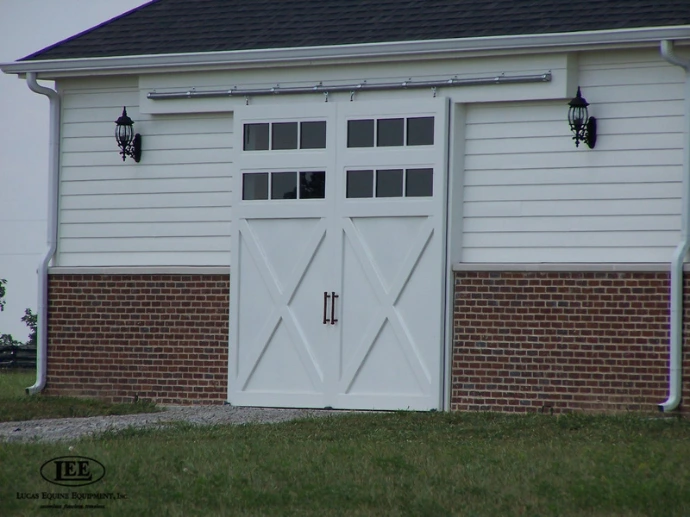 White barn with gray carriage-style doors featuring X-brace pattern and multi-pane windows
