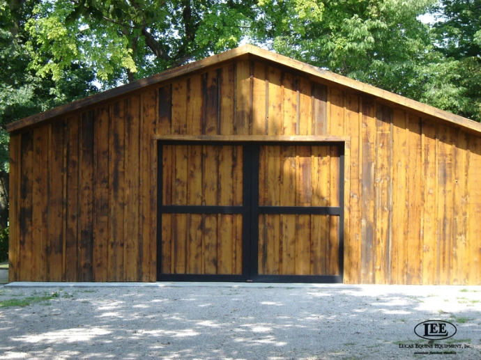 Natural wood barn with large sliding doors featuring upper window sections