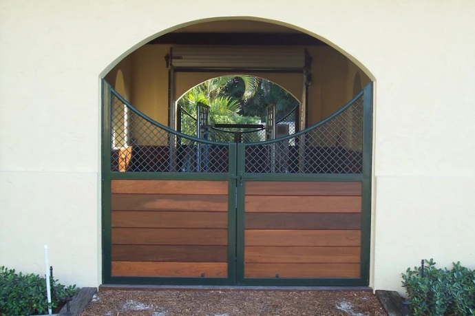 Arched double doors with dark green frame and horizontal wood planks in stucco archway