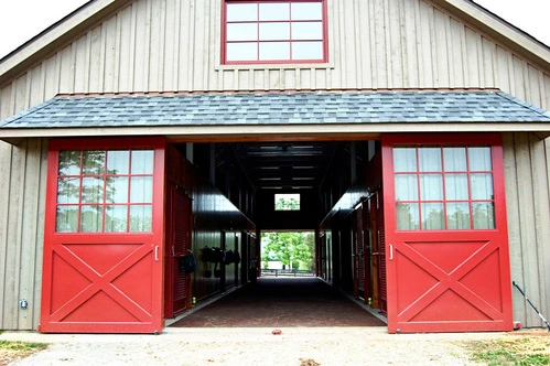 Red barn with white trim featuring red X-pattern sliding doors and window panels
