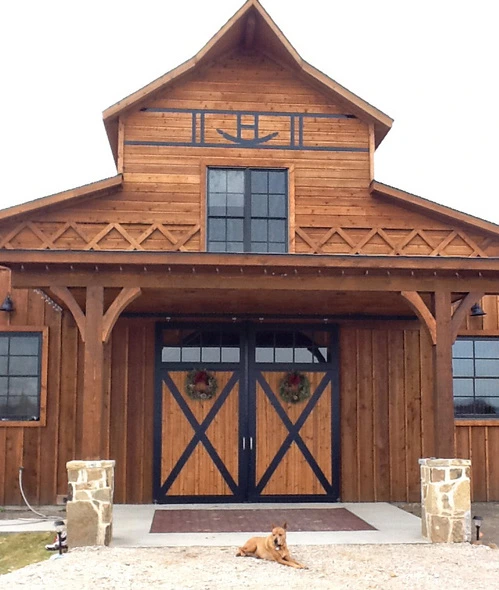 Natural wood barn with X-pattern double doors under timber-frame gable