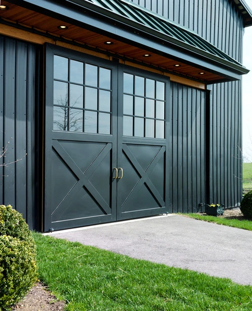 Dark gray double doors with X-pattern design on corrugated metal barn exterior