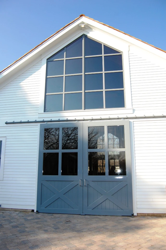 White horizontal siding barn with black framed multi-pane windows in two-story configuration