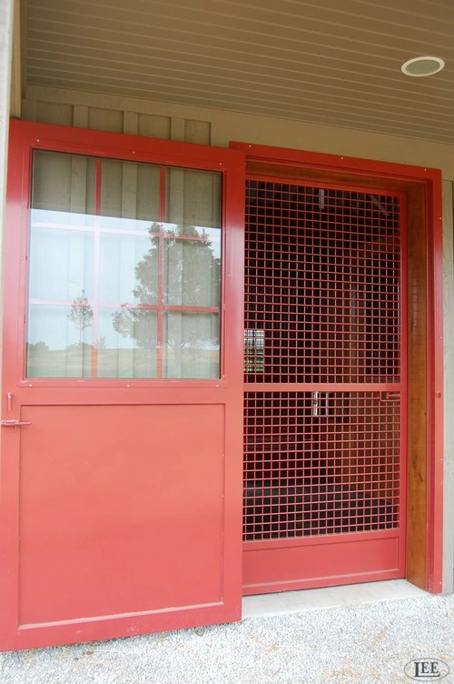 Red metal Dutch-style stall door with frosted glass upper panel and wire mesh lower section