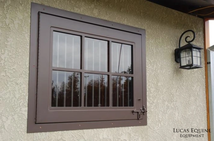 Bronze or brown metal window with grid pattern and exterior lantern on cream stucco wall