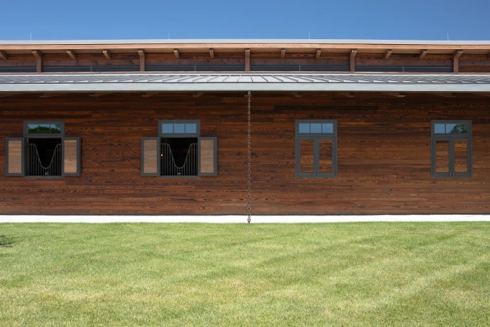 Natural wood barn with horizontal siding featuring multiple window styles including grid pattern designs