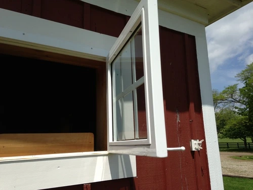 Red barn exterior with partially open window and red shutter revealing interior space