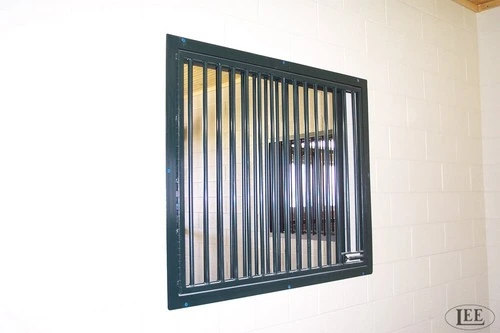 Dark charcoal metal window with vertical bars mounted on cream interior wall