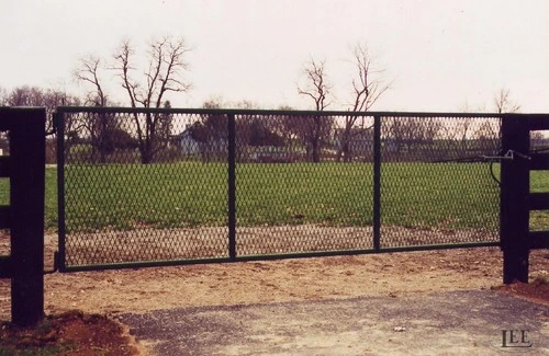 Black metal gate with mesh infill closed across paddock entrance during winter season