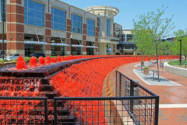 Commercial building exterior with black metal vertical bar railing along curved walkway, red mulch landscaping and construction equipment visible