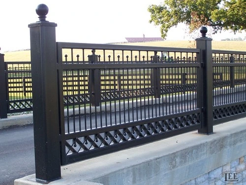 Black ornamental metal railing or fence with decorative square lattice pattern along white concrete retaining wall